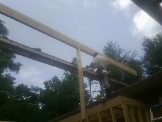 Carpenter setting a ridge beam over a new addition frame — Ice Dam Removal by Roofing Brothers in Beaufort