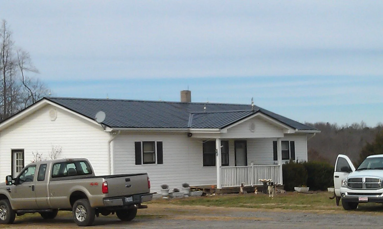 Finished dark metal roof on a white ranch home with work trucks parked in Beaufort